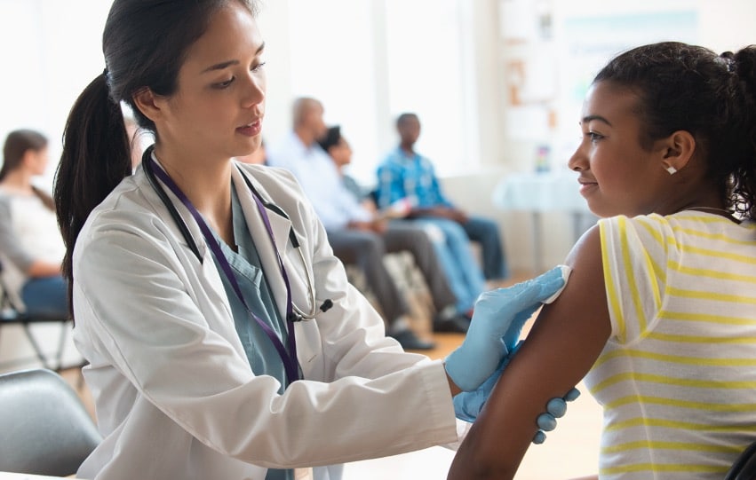 Female Asian doctor inspecting the arm of a young black female.