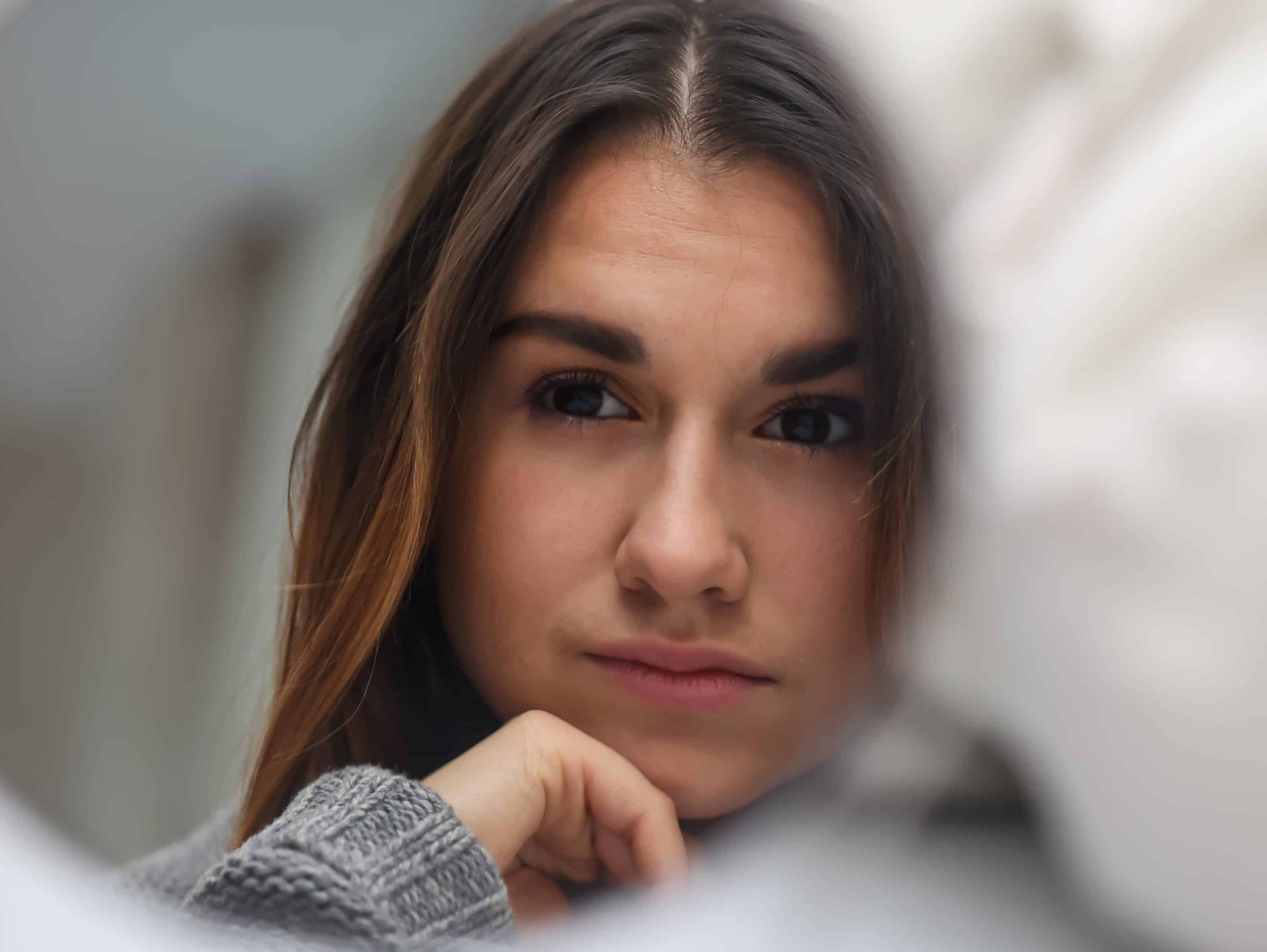 Young white woman with long hair, looking at her face in a mirror