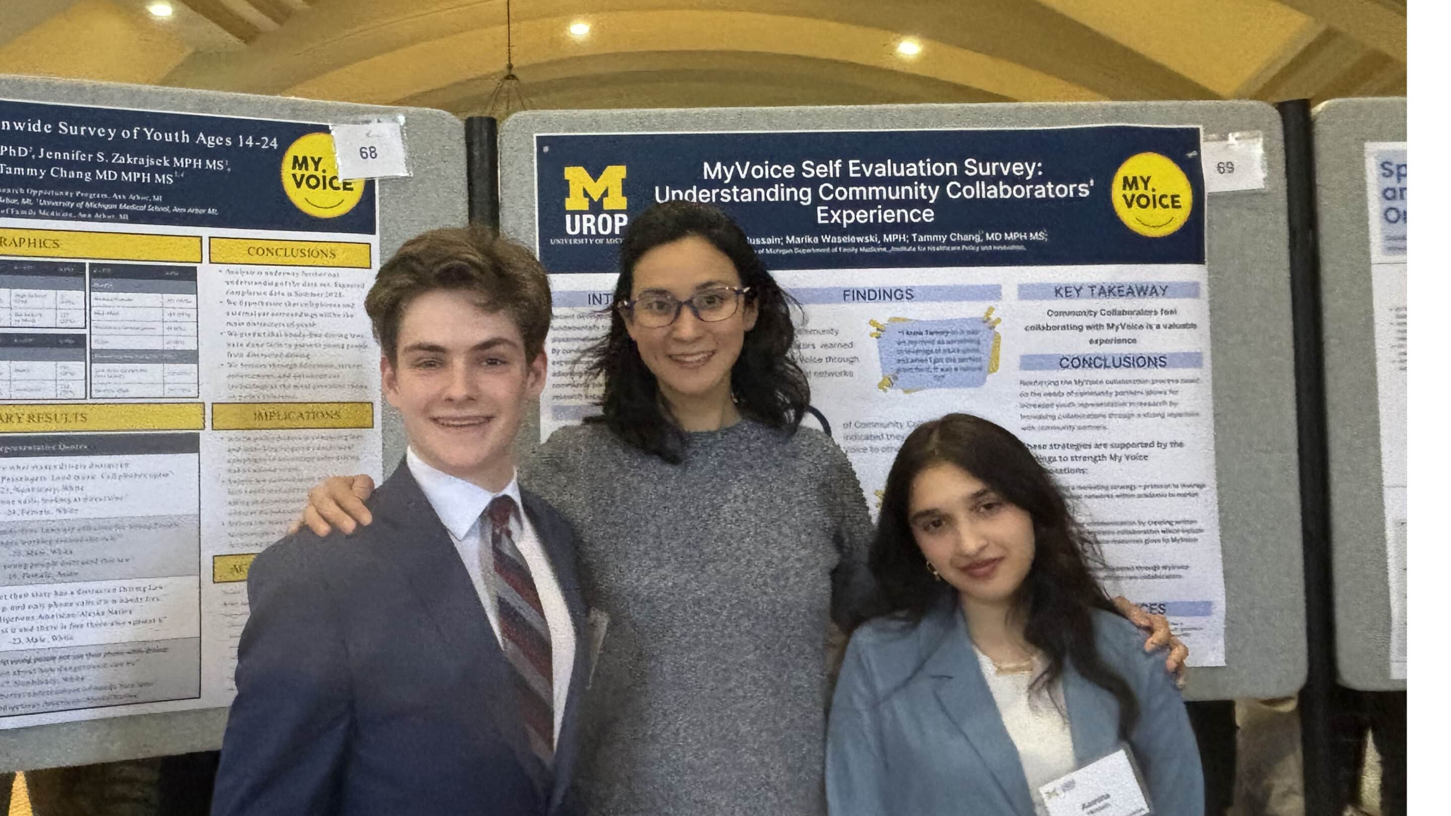 Group photo showing, from left to right, University of Michigan student Carson Downer, a young man in a navy blazer and tie; Dr. Tammy Chang, a woman with dark hair and glasses, wearing a grey sweater, and University of Michigan student Aamina Hussein, a young women with dark hair, wearing a blue-grey jacket, pictured in front of two research posters.