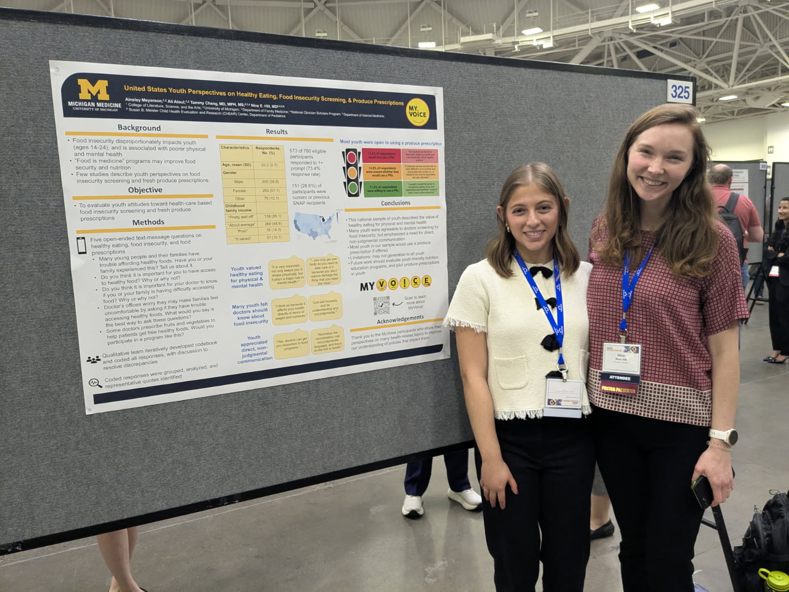 Group photo showing, from left to right, University of Michigan student Carson Downer, a young man in a navy blazer and tie; Dr. Tammy Chang, a woman with dark hair and glasses, wearing a grey sweater, and University of Michigan student Aamina Hussein, a young women with dark hair, wearing a blue-grey jacket, pictured in front of two research posters.